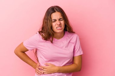Pembe arka planda karaciğer ağrısı çeken, karnı ağrıyan beyaz bir kadın..