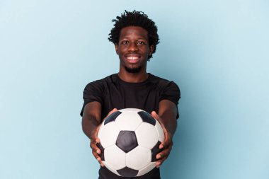 Genç Afro-Amerikan futbol oynayan adam mavi arka planda izole edilmiş.
