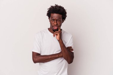 Beyaz arka planda izole edilmiş genç Afrikalı Amerikalı şüpheli ve şüpheci bir ifadeyle yana bakıyor..