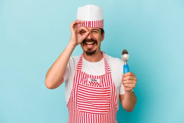 Beyaz tenli genç, mavi arka planda bir kepçe tutuyor. Heyecanlı, tamam mı?.