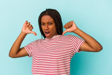 Mavi arka planda izole edilmiş genç Afrikalı Amerikalı kadın gururlu ve kendinden emin hissediyor, örnek olarak.
