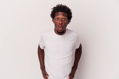 Genç Afro-Amerikalı bir adam beyaz arka planda izole edilmiş, gördüğü bir şey yüzünden şoka uğruyor..