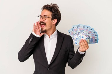 Beyaz arka planda izole edilmiş banknotlar tutan genç beyaz bir adam bağırıyor ve avuç içini açık tutuyor..