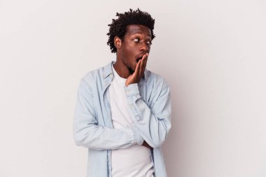 Beyaz arka planda izole edilmiş genç Afrikalı Amerikalı adam esniyor. Ağzını eliyle kapatan yorgun bir hareket sergiliyor..