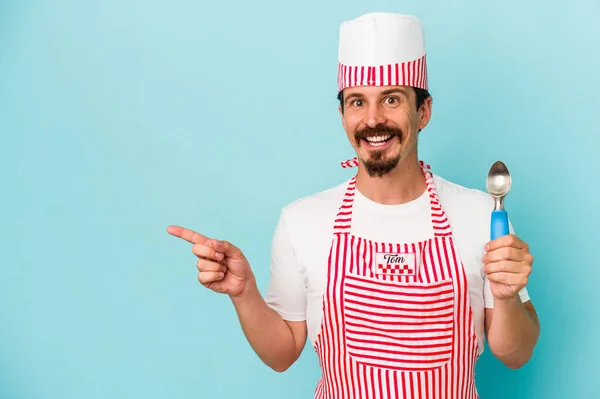 Young Caucasian Maker Holding Scoop Isolated Blue Background Smiling Pointing — Stock Photo, Image