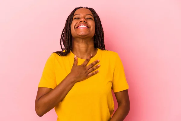 ピンクを背景に孤立した若いアフリカ系アメリカ人女性は大声で手を胸に保つ笑い — ストック写真