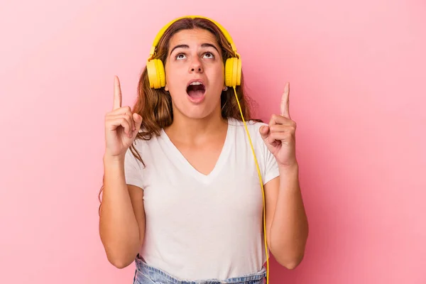 Joven Mujer Caucásica Escuchando Música Aislada Sobre Fondo Rosa Apuntando — Foto de Stock