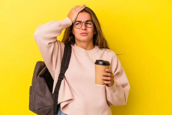 年轻的高加索女学生抱着被黄色背景隔离的咖啡感到震惊 她想起了重要的相遇 — 图库照片