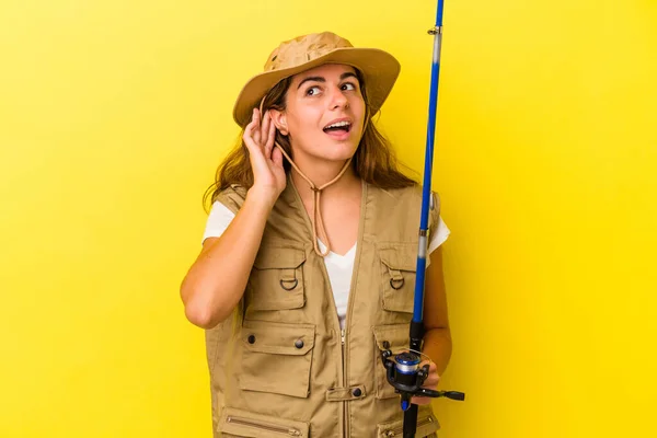 Young Caucasian Fisherwoman Holding Rod Isolated Yellow Background Trying Listening — Stock Photo, Image