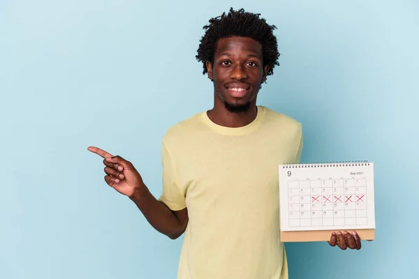 Mladý Africký Američan Drží Kalendář Izolovaný Modrém Pozadí Usmívá Ukazuje — Stock fotografie