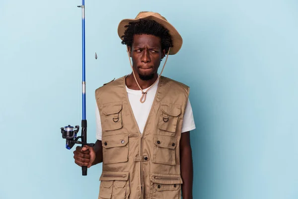 Молодий Афроамериканський Рибалка Який Тримає Палицю Ізольовану Синьому Фоні Збентеженою — стокове фото