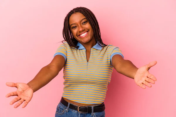 被粉色背景隔离的年轻的非洲裔美国女人表现出一种受欢迎的表情 — 图库照片