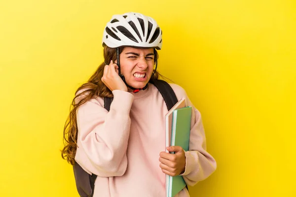 若いですCaucasian学生女性身に着けていますAバイクヘルメット絶縁上の黄色の背景カバー耳で手 — ストック写真