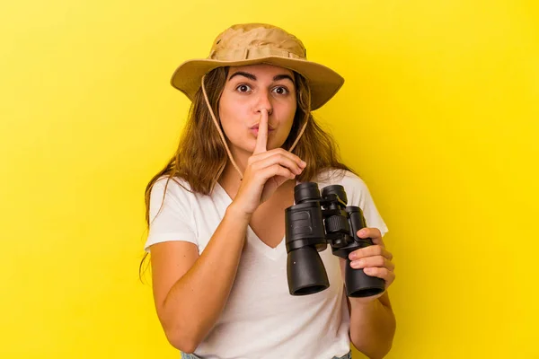 Mladá Běloška Držící Dalekohled Izolovaný Žlutém Pozadí Držící Tajemství Nebo — Stock fotografie