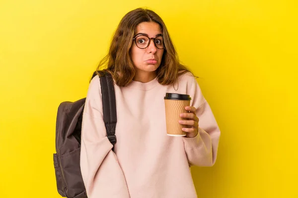 Jovem Estudante Caucasiano Segurando Café Isolado Fundo Amarelo Encolhe Ombros — Fotografia de Stock