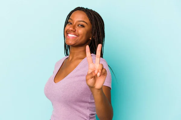 年轻的非洲裔美国女人 被蓝色背景隔离 快乐而无忧无虑 用手指展示和平的象征 — 图库照片