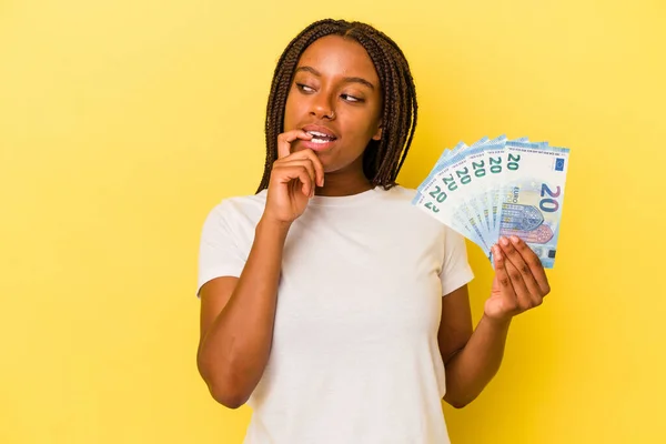 Mladá Africká Američanka Drží Bankovky Izolované Žlutém Pozadí Uvolněně Přemýšlet — Stock fotografie