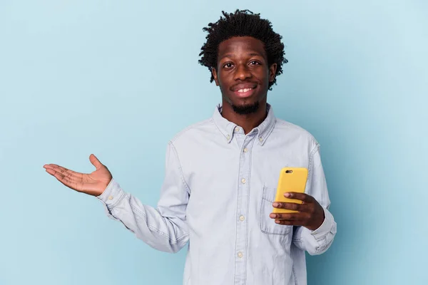 年轻的非洲裔美国人 手持蓝色背景的手机 手掌上有一个复制空间 腰部有另一只手 — 图库照片