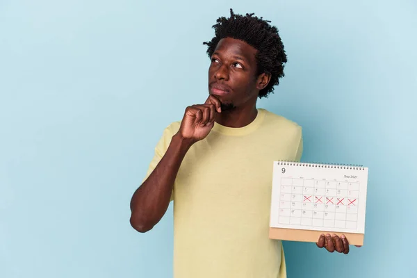 Jonge Afro Amerikaanse Man Houdt Kalender Geïsoleerd Blauwe Achtergrond Kijken — Stockfoto