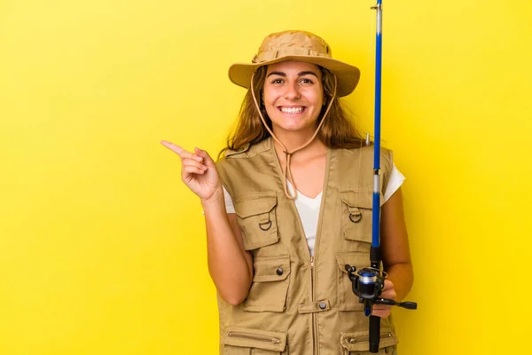 Young Caucasian Fisherwoman Holding Rod Isolated Yellow Background Smiling Pointing — Stock Photo, Image