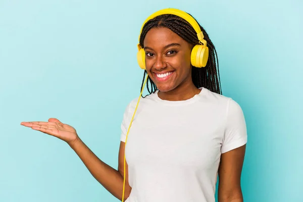 Jovem Afro Americana Ouvindo Música Isolada Fundo Azul Mostrando Espaço — Fotografia de Stock