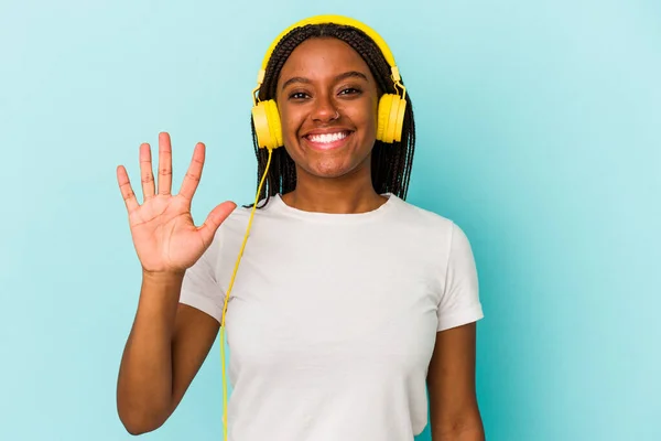 Ung Afroamerikansk Kvinna Lyssnar Musik Isolerad Blå Bakgrund Ler Glad — Stockfoto