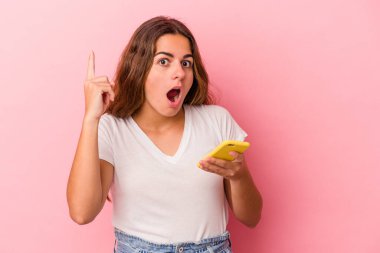 Pembe arka planda izole edilmiş cep telefonu kullanan beyaz bir kadının bir fikri var, ilham verici bir kavram..