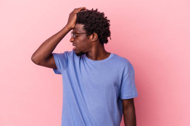 Genç Afrikalı Amerikalı bir adam pembe arka planda izole edilmiş bir şekilde bir şeyi unutuyor. Alnına avuç içi ve kapalı gözlerle tokat atıyor..