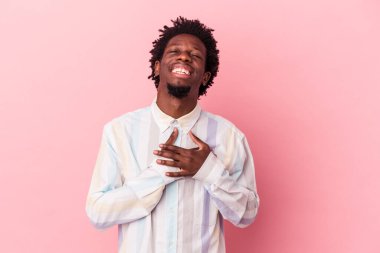 Genç Afro-Amerikan erkeği pembe arka planda izole edilmiş. Gülüyor, elini yüreğine koyuyor, mutluluk kavramını koruyor..