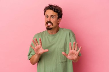 Pembe arka planda izole edilmiş genç beyaz bir adam tiksinti belirtisi gösteren birini reddediyor..