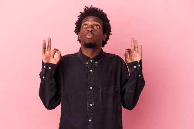 Genç Afrikalı Amerikalı adam pembe arka planda izole edilmiş yoğun bir günün ardından dinleniyor. Yoga yapıyor..