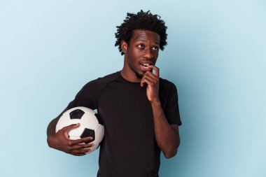 Amerikan futbolu oynayan genç Afrikalı bir adam mavi arka planda izole edilmiş bir şekilde rahat bir şekilde fotokopi odasına bakan bir şeyi düşünüyor..