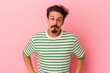 Pembe arka planda soyutlanmış, kafası karışmış, şüpheli ve kararsız genç bir beyaz adam..