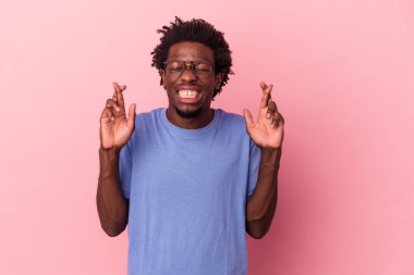 Genç Afrikalı Amerikalı adam pembe arka planda izole edilmiş şans diliyor.