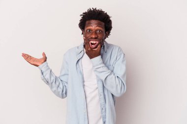 Beyaz arka planda izole edilmiş genç Afro-Amerikalı bir adam avuç içinde fotokopi alanı tutuyor, el üstünde tutuyor. Şaşırmış ve mutlu..