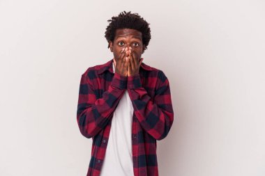 Beyaz arka planda izole edilmiş genç Afrikalı Amerikalı adam şok olmuş, ağzı ellerle kaplanmış, yeni bir şey keşfetmeye hevesli..