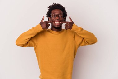 Beyaz arka planda izole edilmiş genç Afrikalı Amerikalı adam gülümsüyor, parmaklarını ağıza doğrultuyor..