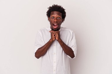 Genç Afro-Amerikalı adam beyaz arka planda izole edilmiş şans için dua ediyor, şaşırmış ve ağzını açıyor..