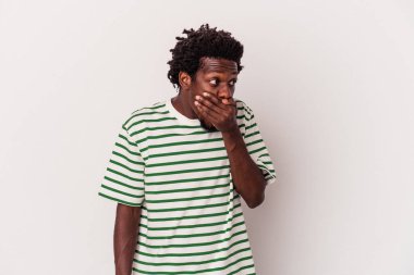 Genç Afrikalı Amerikalı bir adam beyaz arka planda izole edilmiş. Düşünceli bir şekilde bir fotokopi odasına bakıyor. Ağzını eliyle kapatıyor..