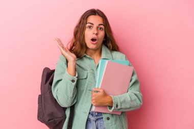 Pembe arka planda kitap tutan genç beyaz kadın şaşırmış ve şok olmuştu..