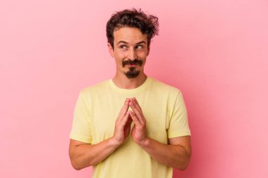 Kafkasyalı genç bir adam pembe arka planda izole edilmiş bir plan yapıyor, bir fikir kuruyor..