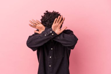 Genç Afrikalı Amerikalı adam pembe arka planda izole edilmiş iki kolu çapraz tutuyor, inkar kavramı.