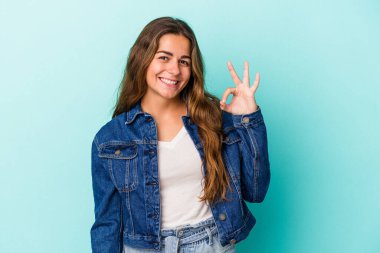 Kafkasyalı genç bir kadın mavi arka planda izole edilmiş neşeli ve kendinden emin..