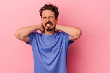 Genç, beyaz bir adam pembe arka planda izole edilmiş. Durağan yaşam tarzından dolayı boyun ağrısı çekiyor..