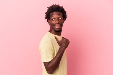 Genç Afrikalı Amerikalı adam pembe arka planda izole edilmiş, başparmak uzakta, gülüyor ve kaygısız..
