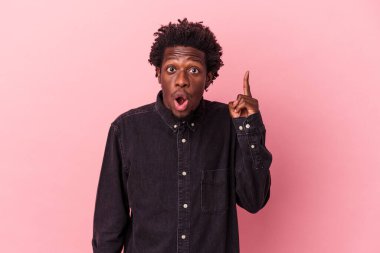 Genç Afro-Amerikalı, pembe arka planda izole edilmiş, ağzı açık, üst tarafı işaret ediyor..