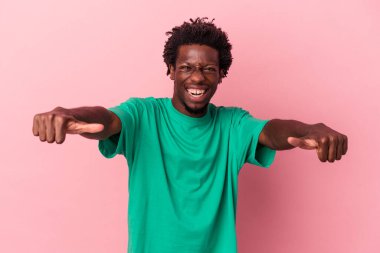 Genç Afro-Amerikalı adam pembe arka planda izole edilmiş. Baş parmağını kaldırıyor, gülümsüyor ve kendinden emin..