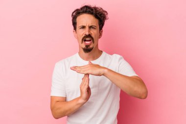 Pembe arka planda izole edilmiş genç beyaz adam bir mola hareketi gösteriyor..