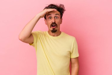 Pembe arka planda izole edilmiş genç beyaz adam yüksek sesle bağırıyor, gözleri açık ve elleri gergin tutuyor..