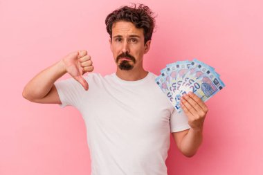 Elinde banknotlar tutan beyaz bir adam pembe arka planda izole edilmiş, hoş olmayan bir jest gösteriyor, kabul etmiyor. Anlaşmazlık konsepti.